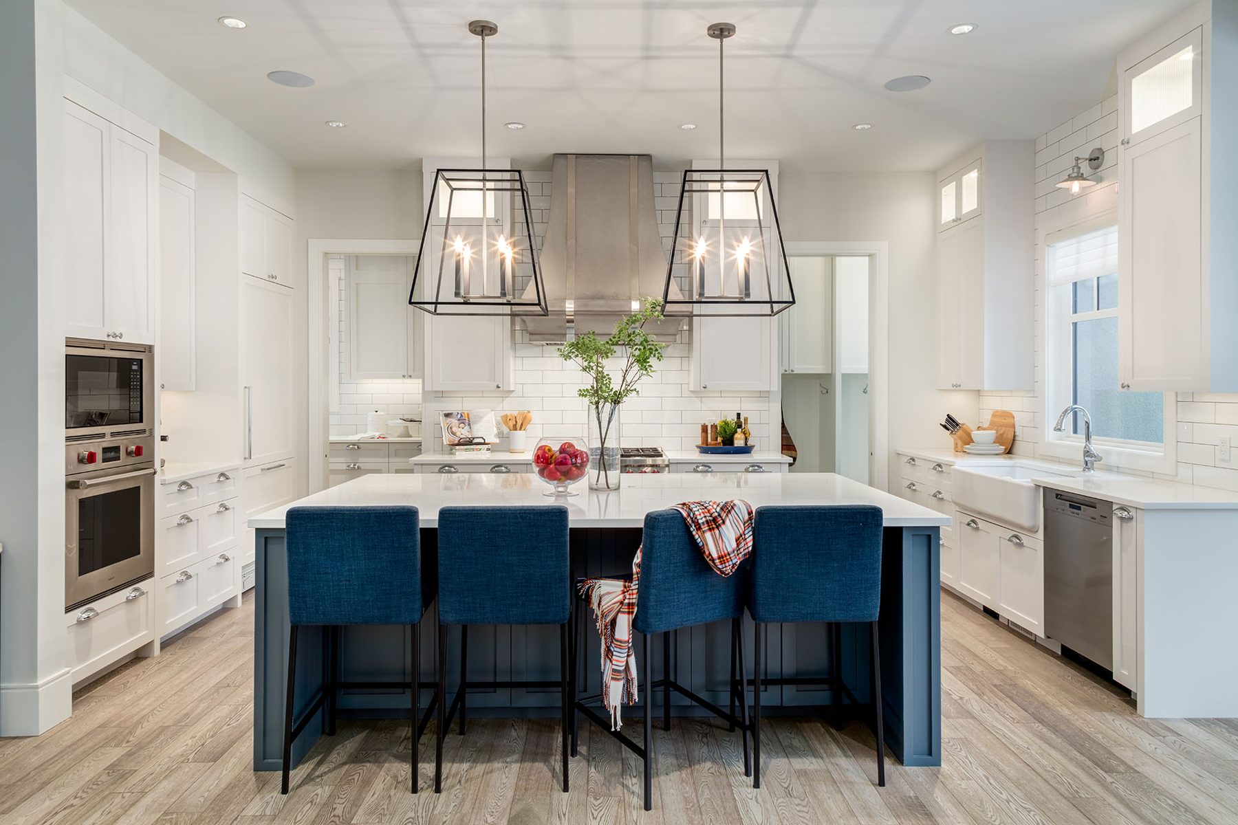 Modern kitchen island with blue stools, white cabinets, stainless steel appliances — Cleret Velour