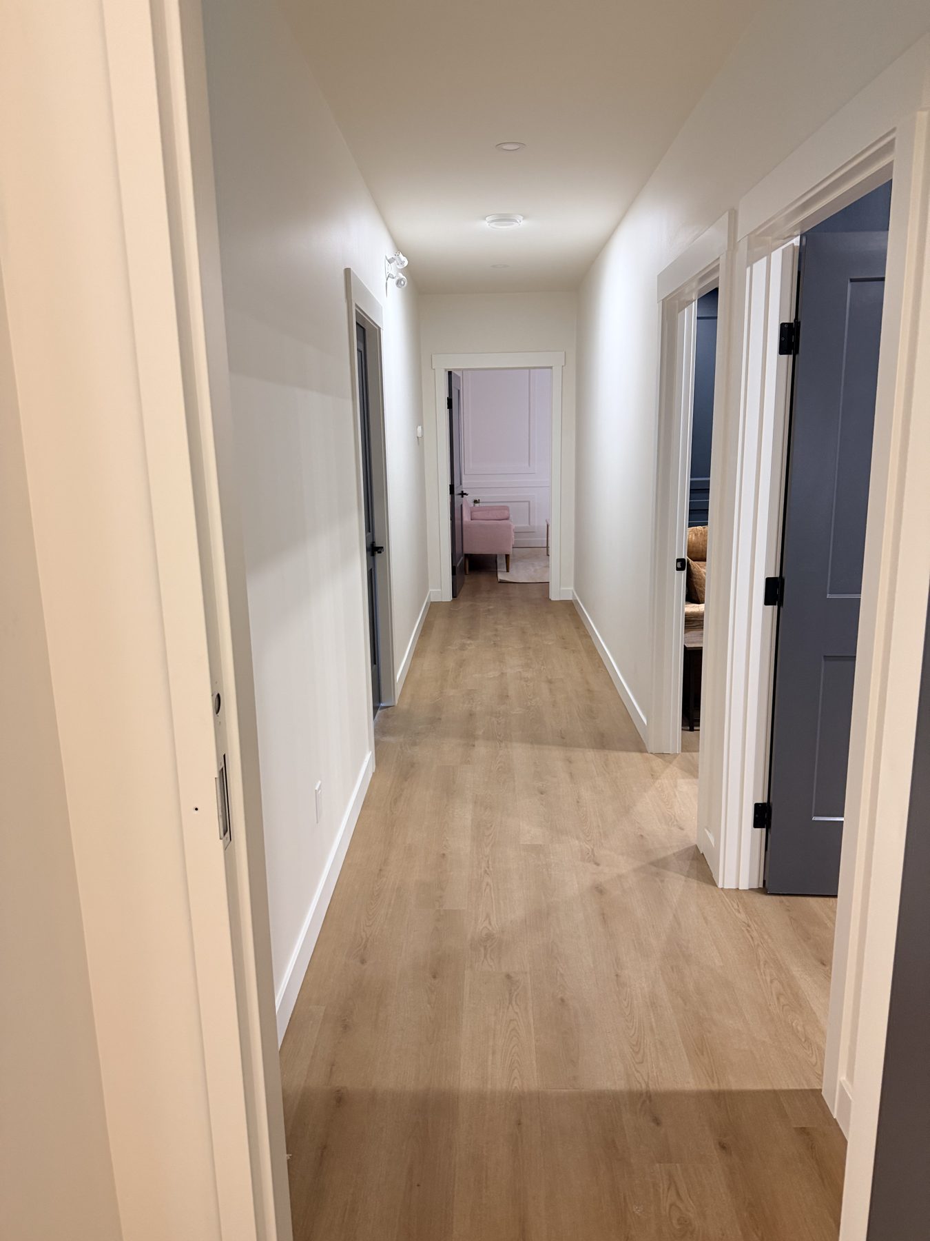 Hallway with light wood floors, white walls, and dark doors — The Barron Venue