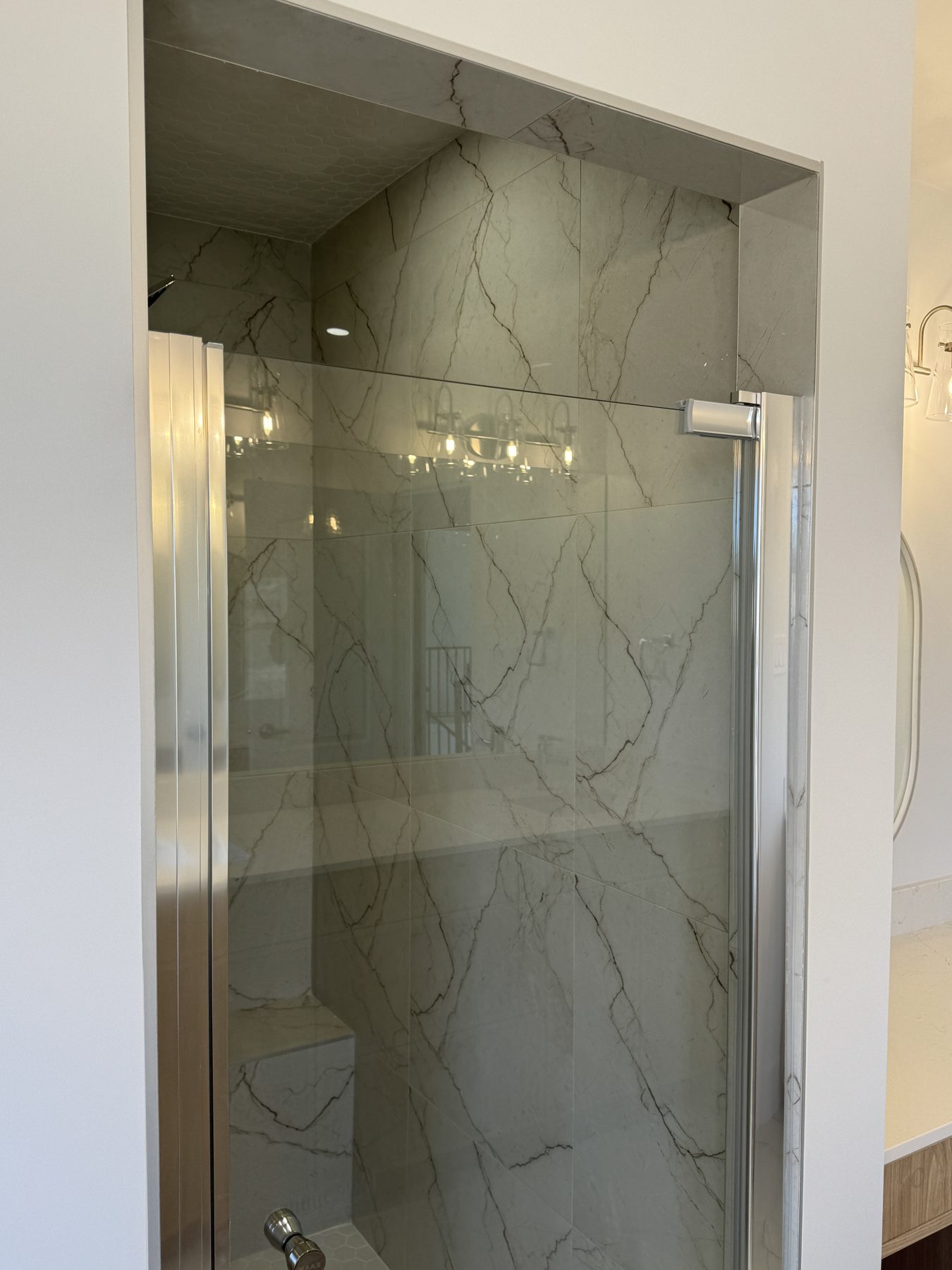 Modern shower enclosure with marble tile and glass door — 14 Lochend Drive, Cochrane