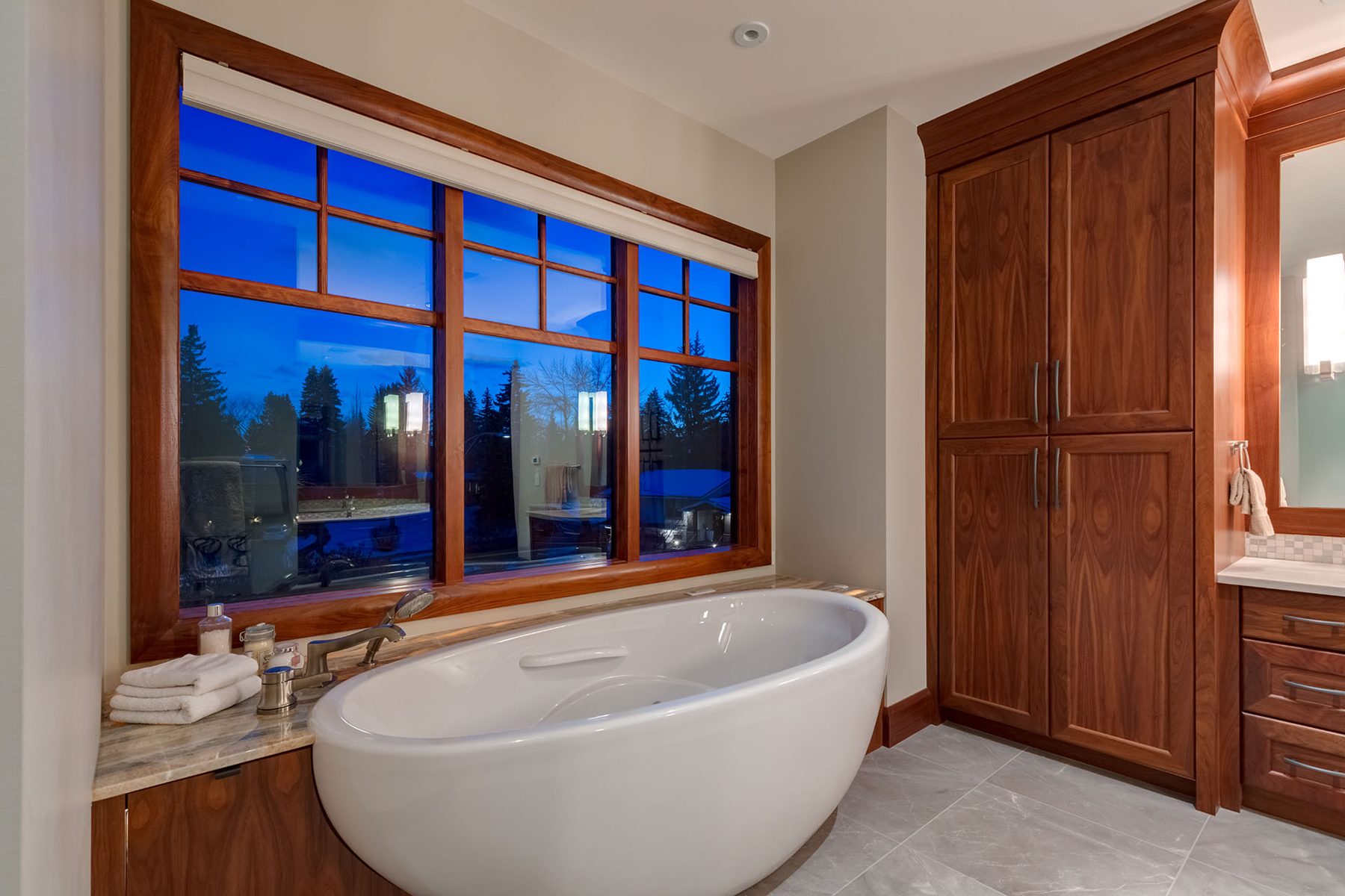 Freestanding tub, wood cabinets, and tile floor in completed bathroom — Oxford