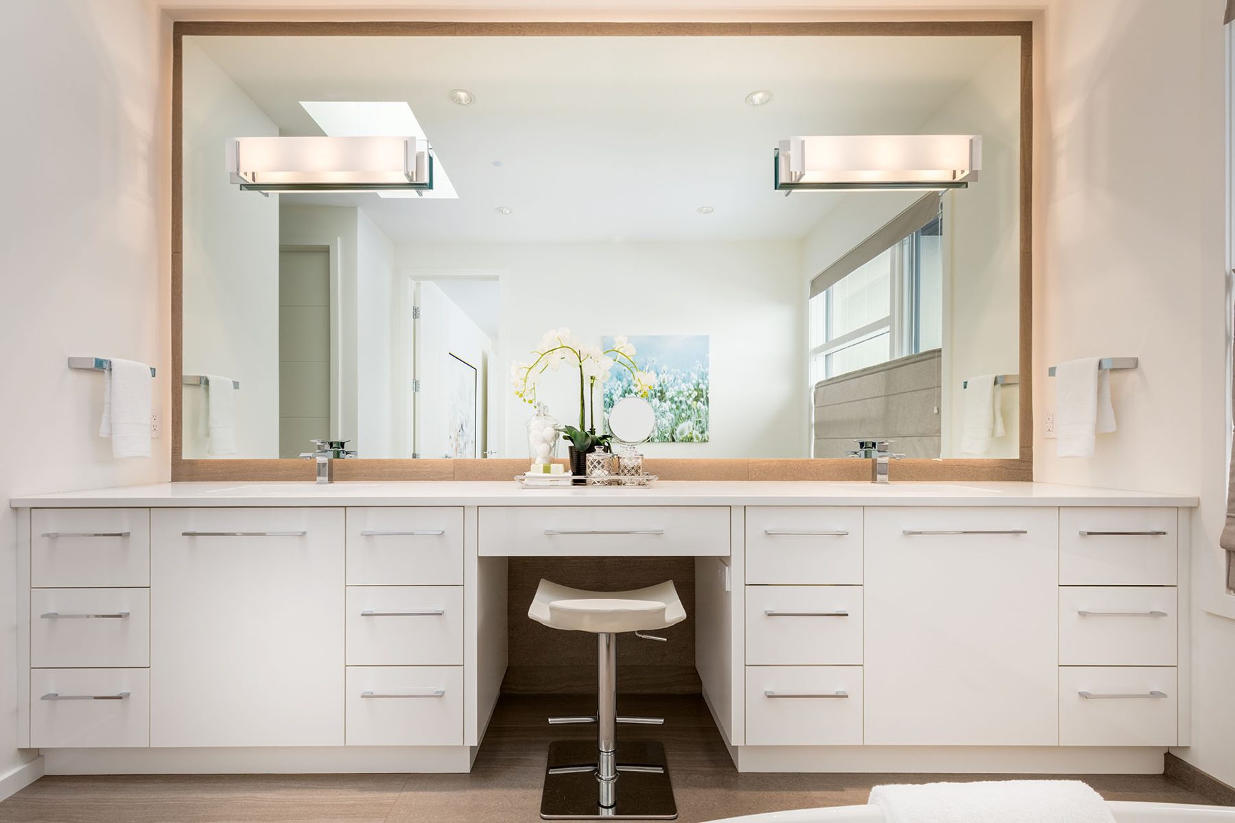 Modern bathroom vanity with white cabinets, double sinks, and a makeup stool — Casa Blanca
