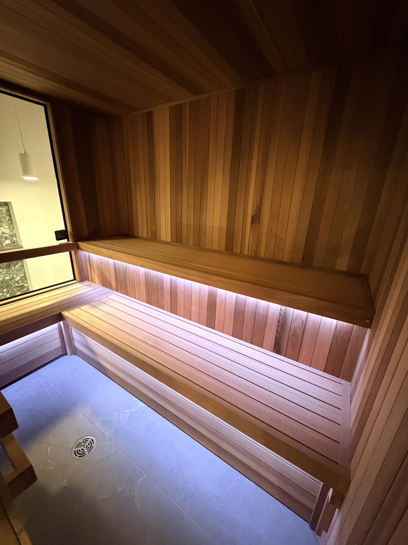Wooden sauna interior with tiered benches and modern LED lighting — Cedar Steam and Spa (Trinity Hills)