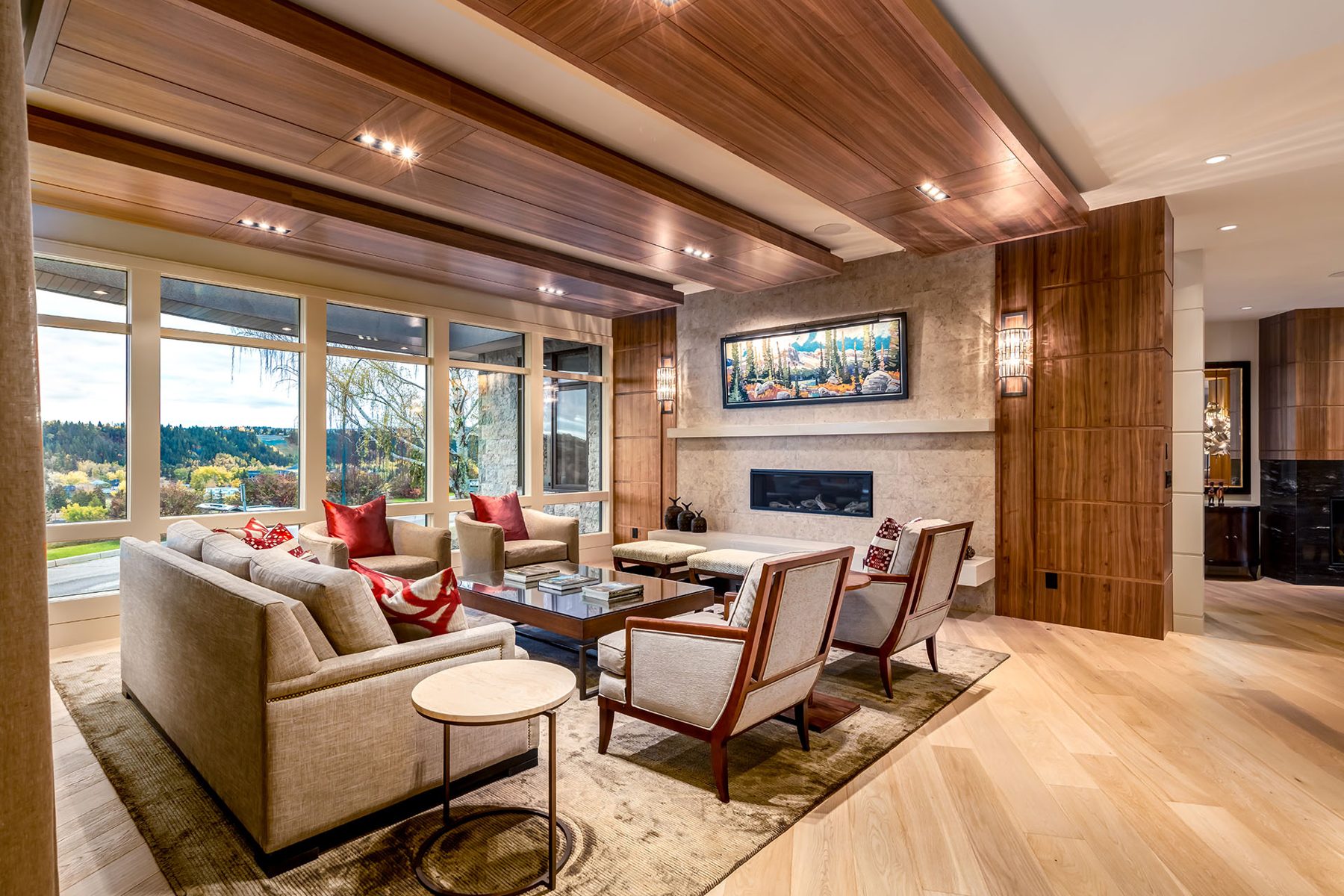 Living room with stone fireplace, wood paneling, and large windows — Evolution