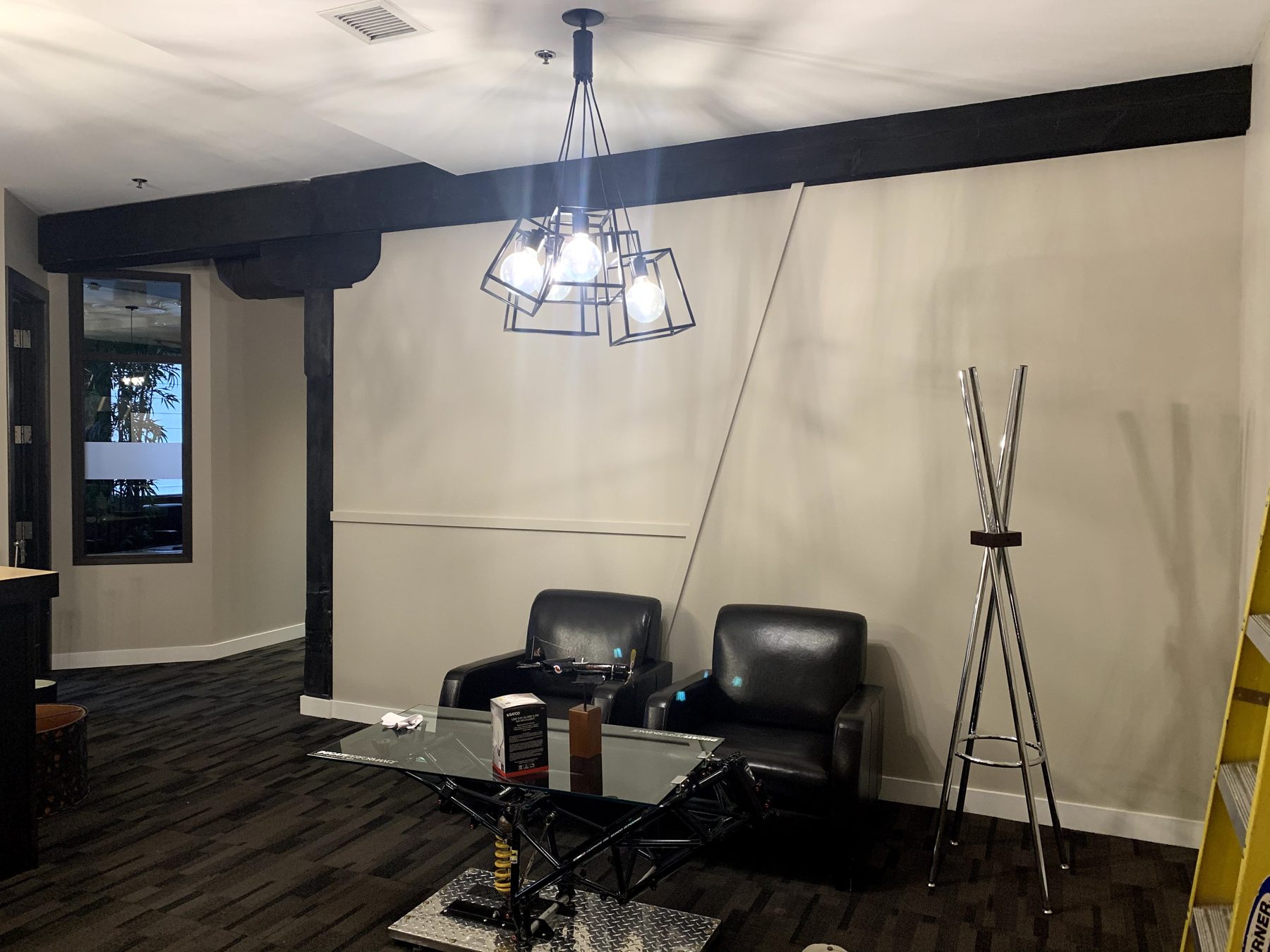 Office waiting area with modern chandelier, two chairs, and glass table — Clearmotive (Victoria Park)