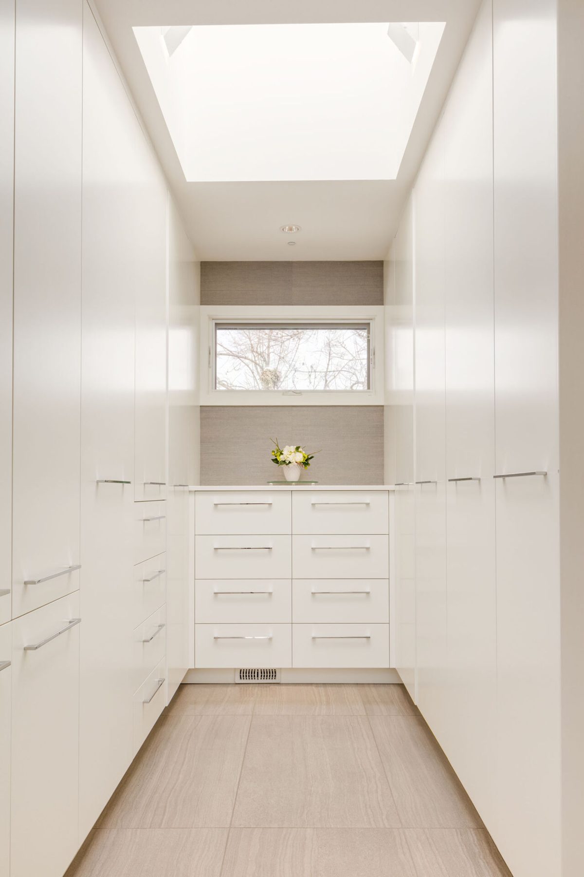 Modern closet with white cabinetry, skylight, and tile floor — Casa Blanca