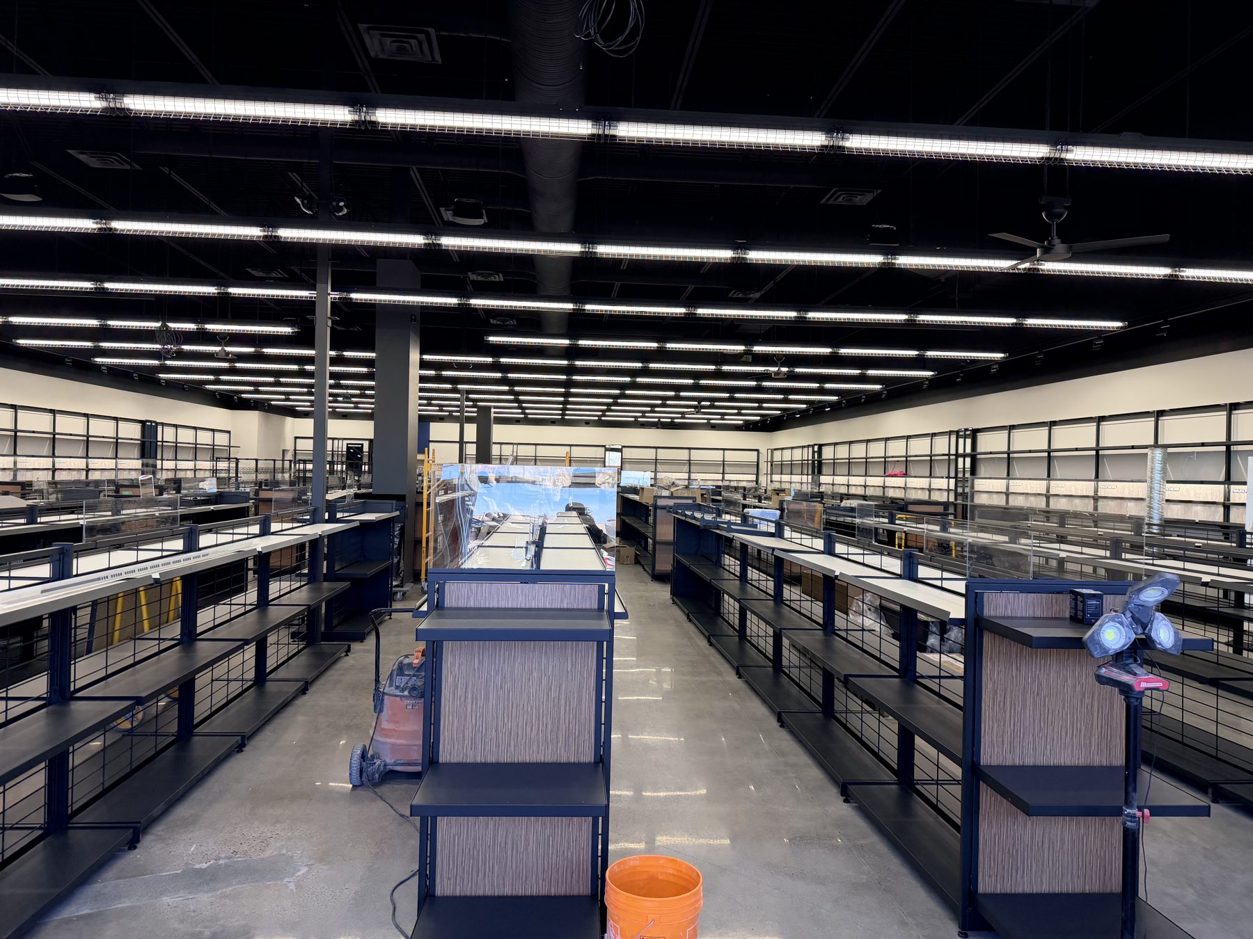 Empty retail space with new shelves, lighting, and construction equipment — Skechers (Signal Hill)