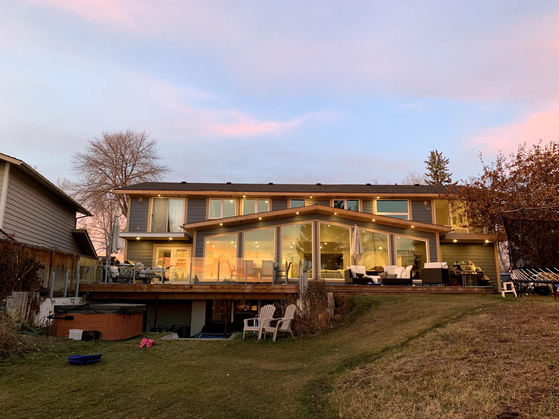 Modern house addition with large windows, wood deck, and hot tub — 7 Midlake Green SE, Calgary