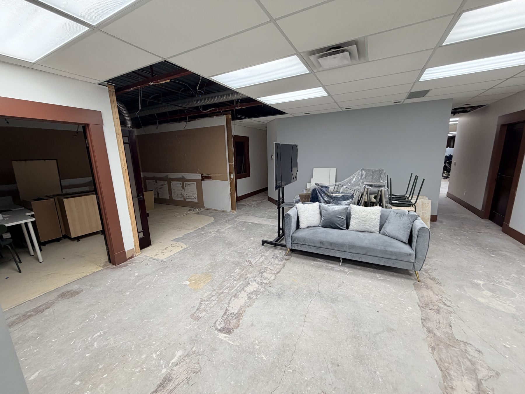 Open office space with exposed ceiling, gray couch, and renovation materials — The Barron Venue