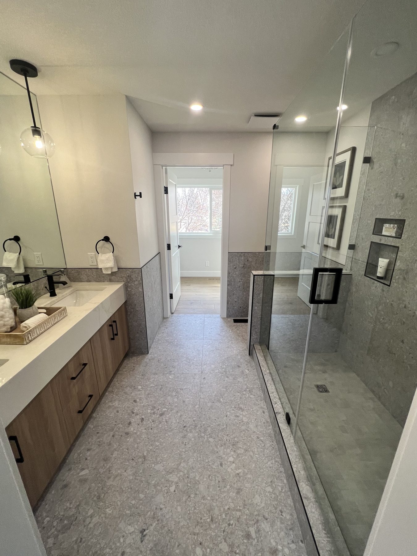Modern bathroom with gray terrazzo floor, vanity, and glass shower enclosure — 720 Lake Twintree Crescent SE, Calgary