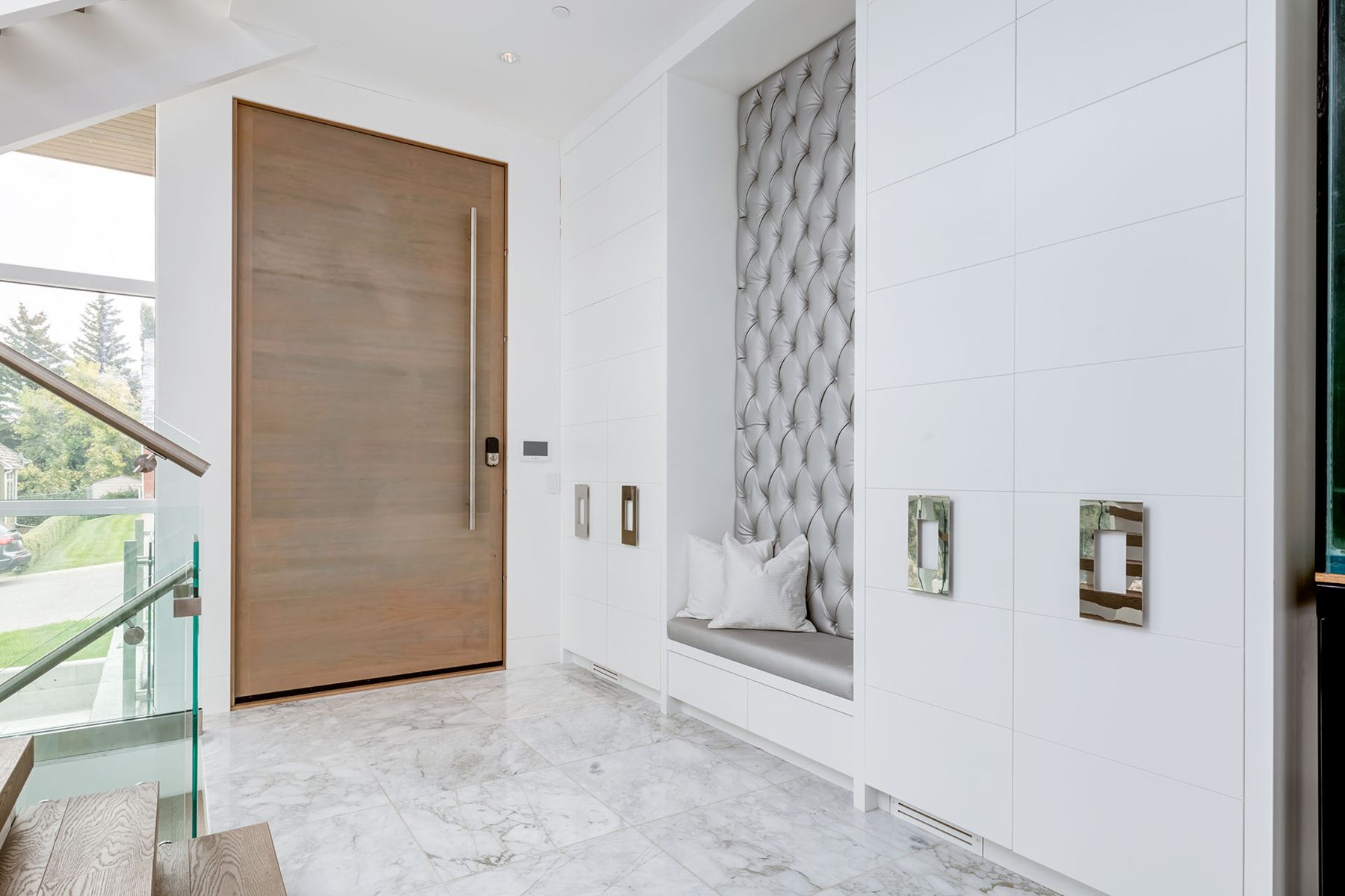 Modern entryway with large wooden door, marble floor, and built-in bench — Germania