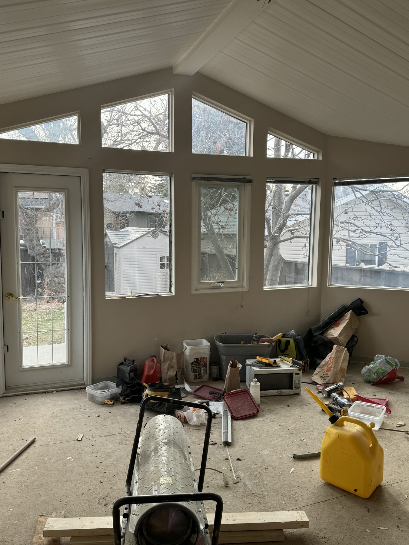 Renovation debris and construction tools in a sunroom with many windows — 188 Lake Adams Crescent SE, Calgary