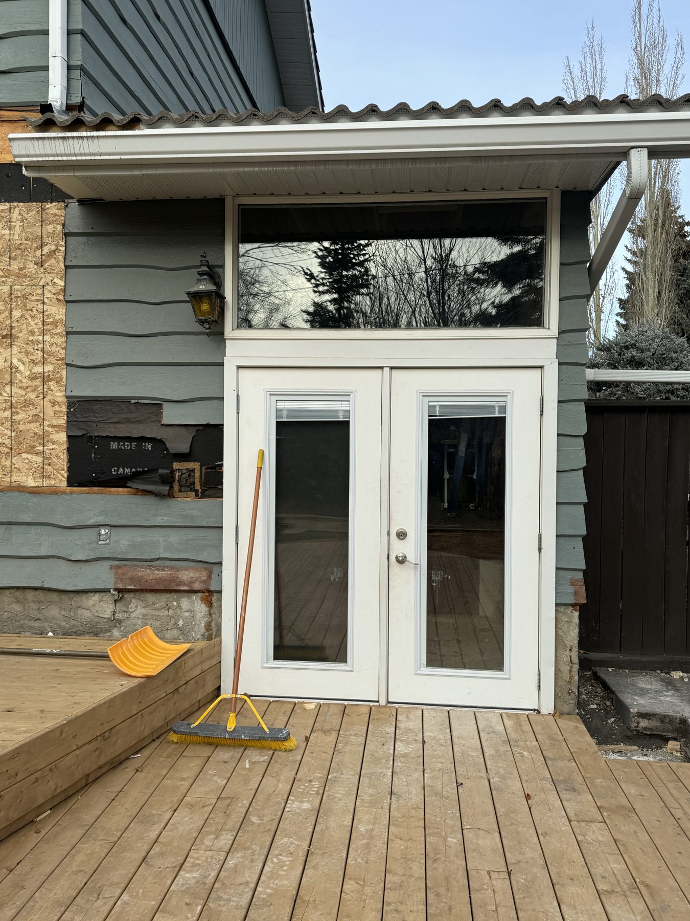 Exterior wall under renovation, showing new deck and doors — 188 Lake Adams Crescent SE, Calgary