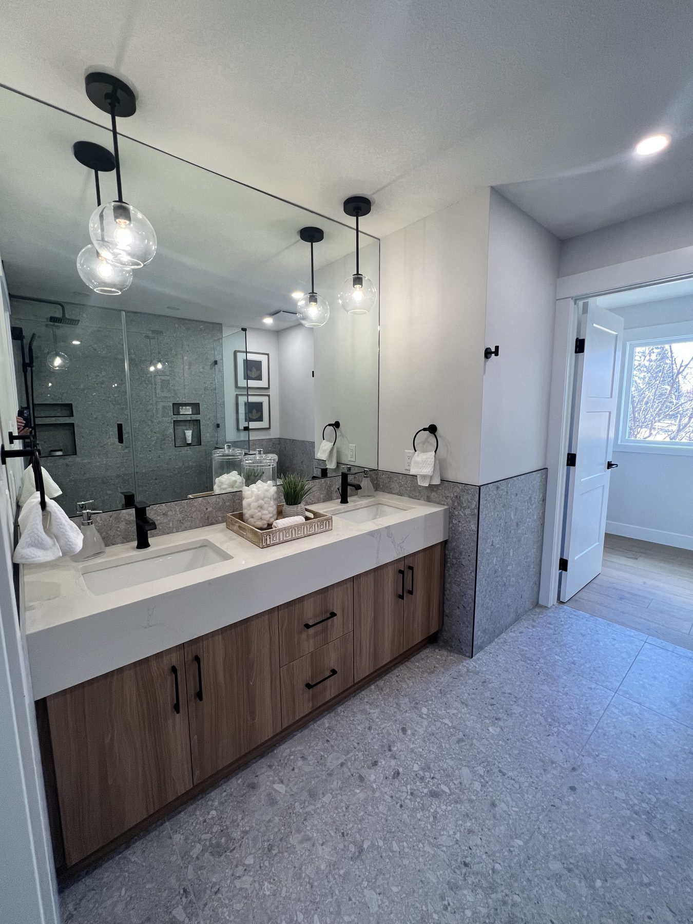 Modern bathroom renovation with double vanity, glass pendant lights, and tile shower — 720 Lake Twintree Crescent SE, Calgary