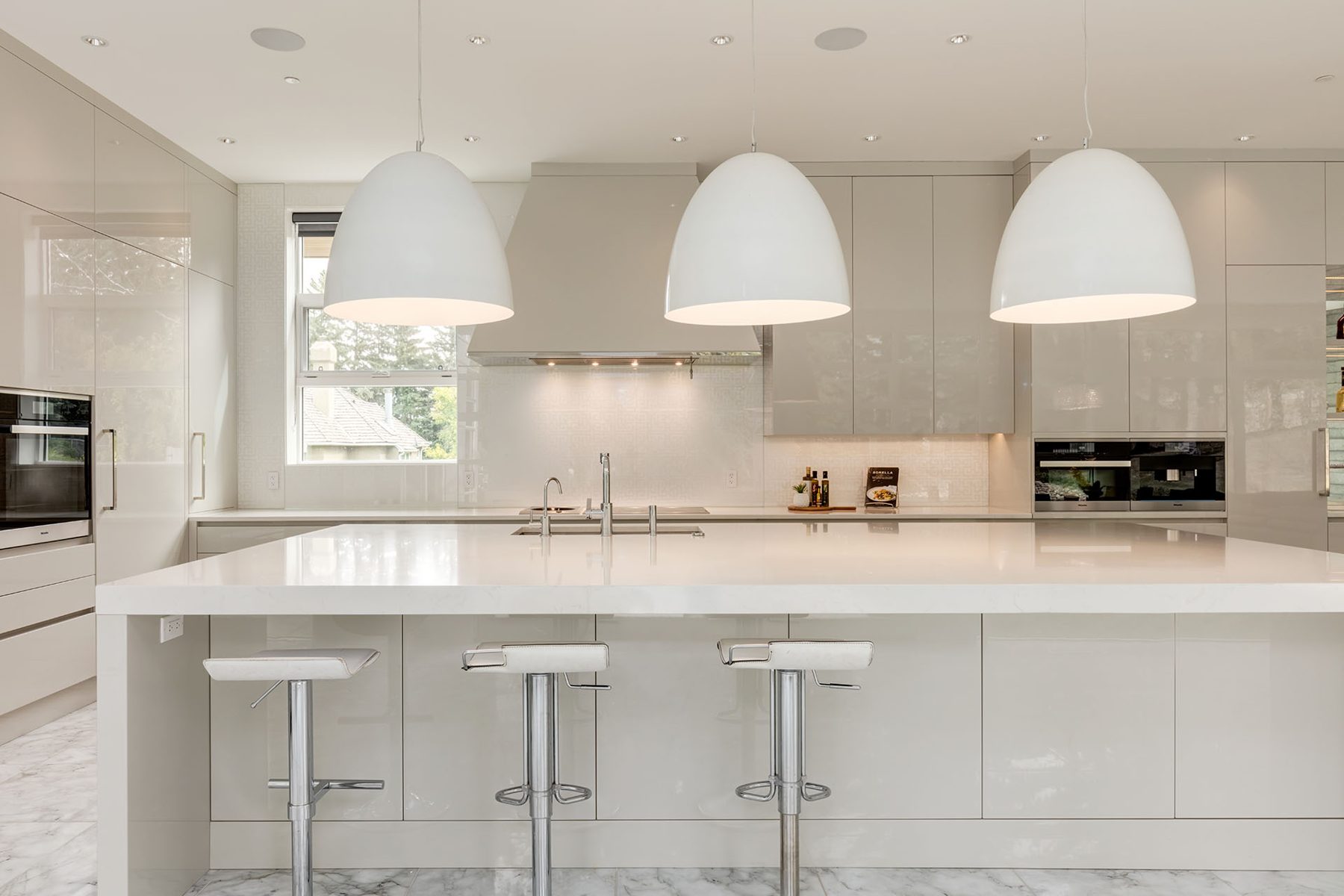 Modern kitchen with white quartz island, pendant lights, and grey cabinetry — Germania