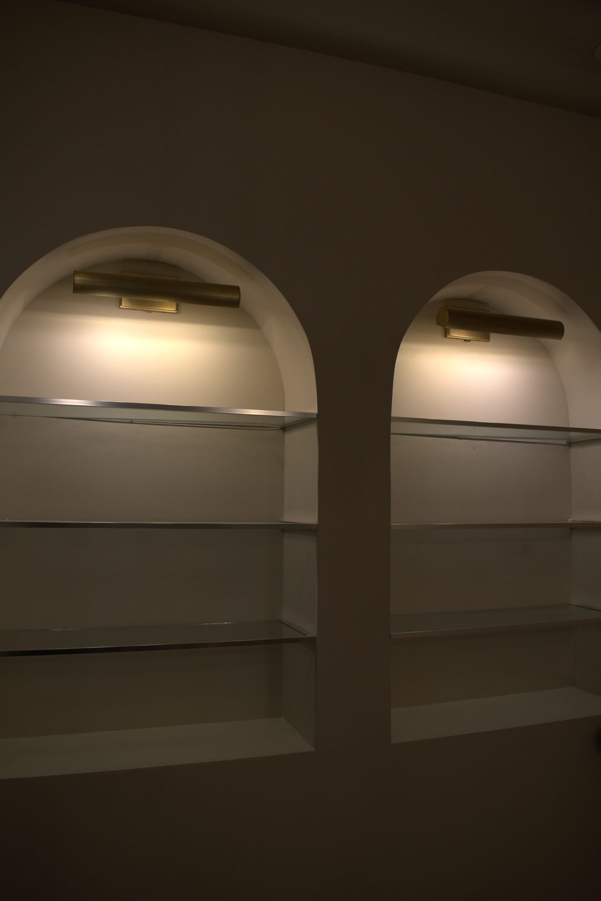 Arched niches with modern brass sconces and glass shelving — Leela Spa (Bankers Hall)