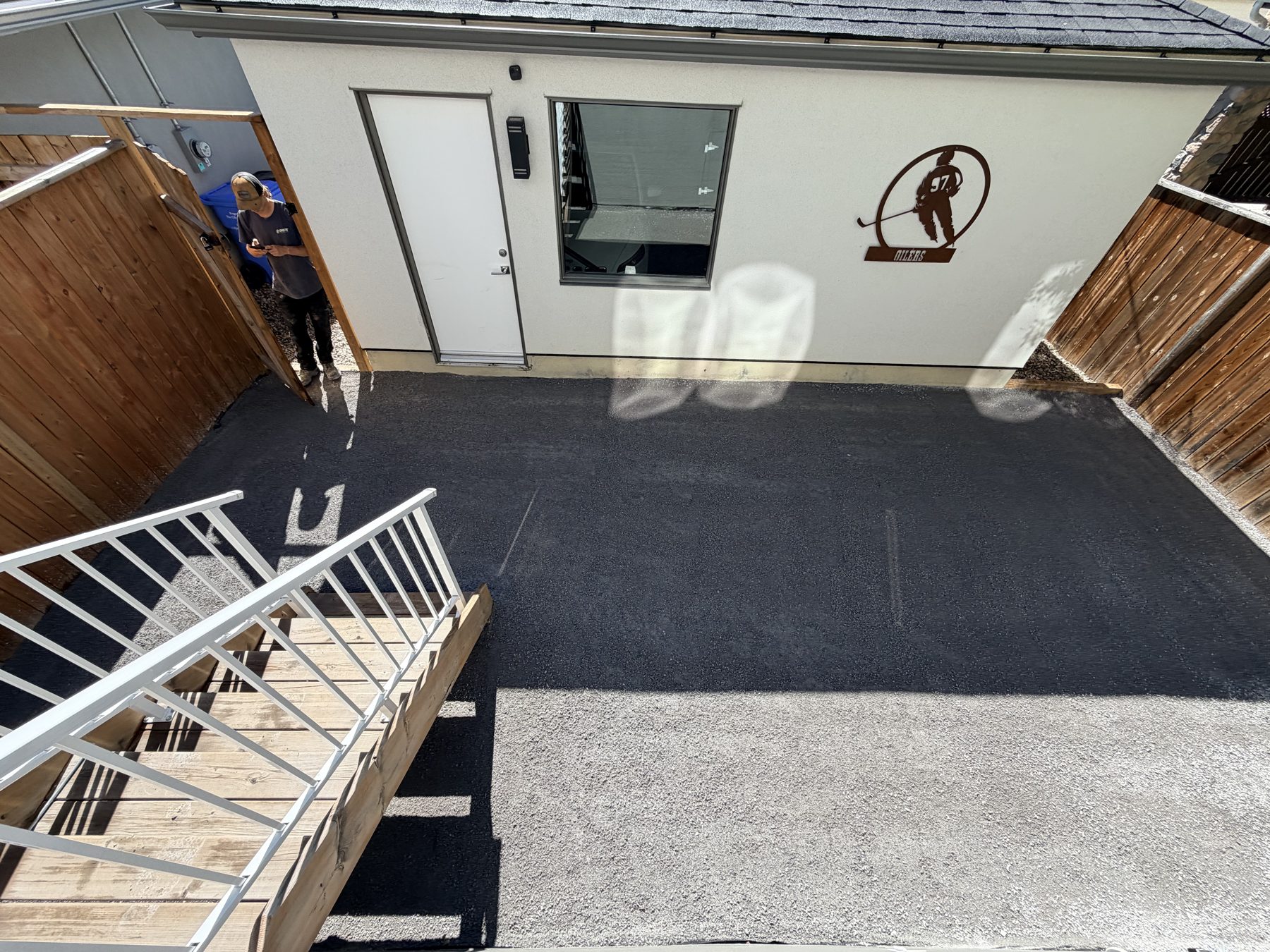 New asphalt driveway next to a building with a white door and window — 3505 41 Street SW, Calgary