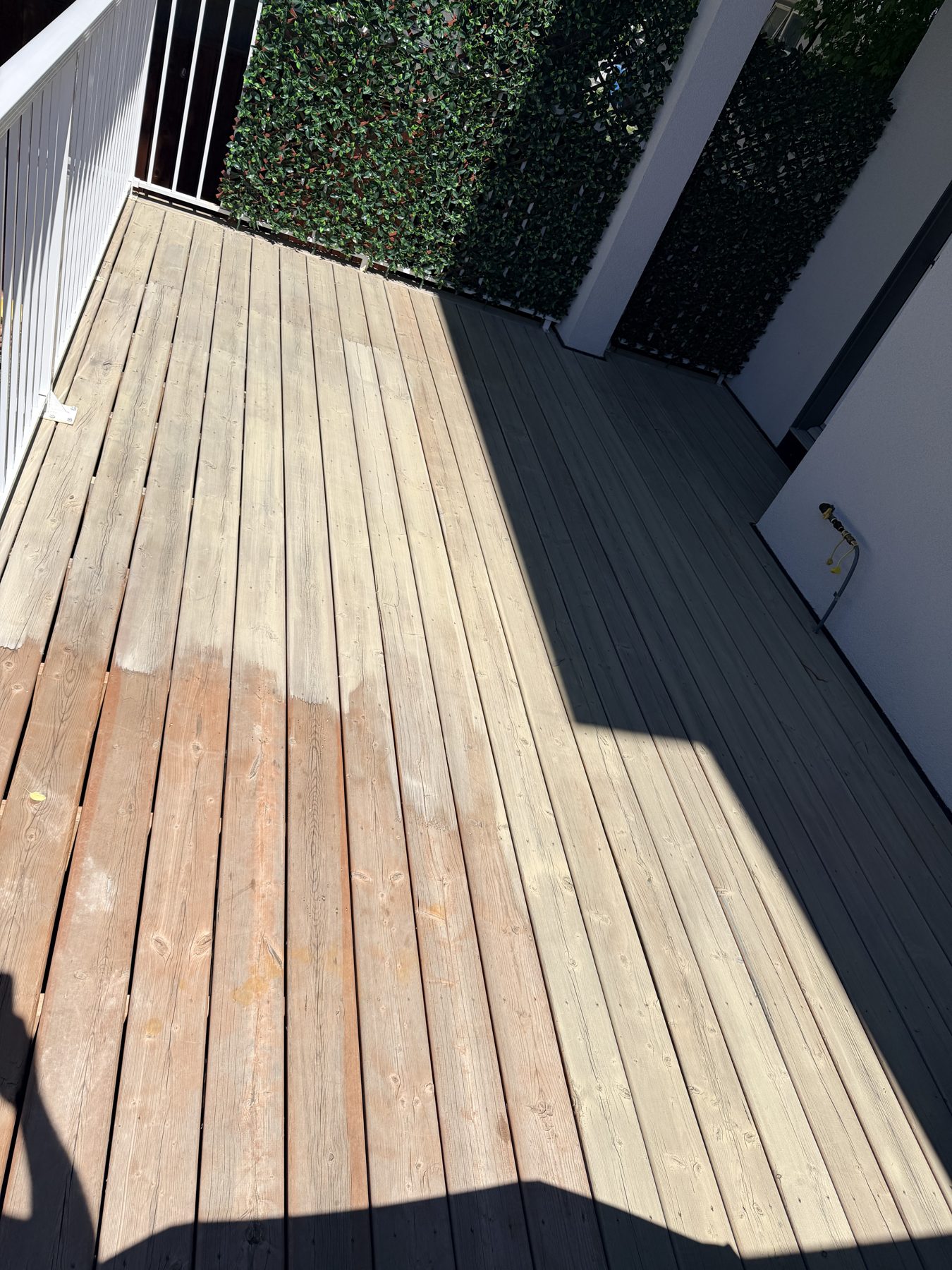 Deck renovation: half-stained wooden boards, white railing, green privacy screen — 3505 41 Street SW, Calgary