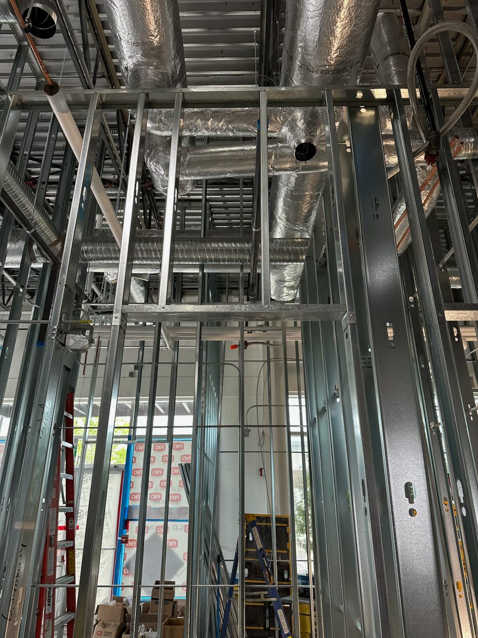 Metal framing, ductwork, and plumbing in an unfinished interior space — Blowers and Grafton (Red Deer)