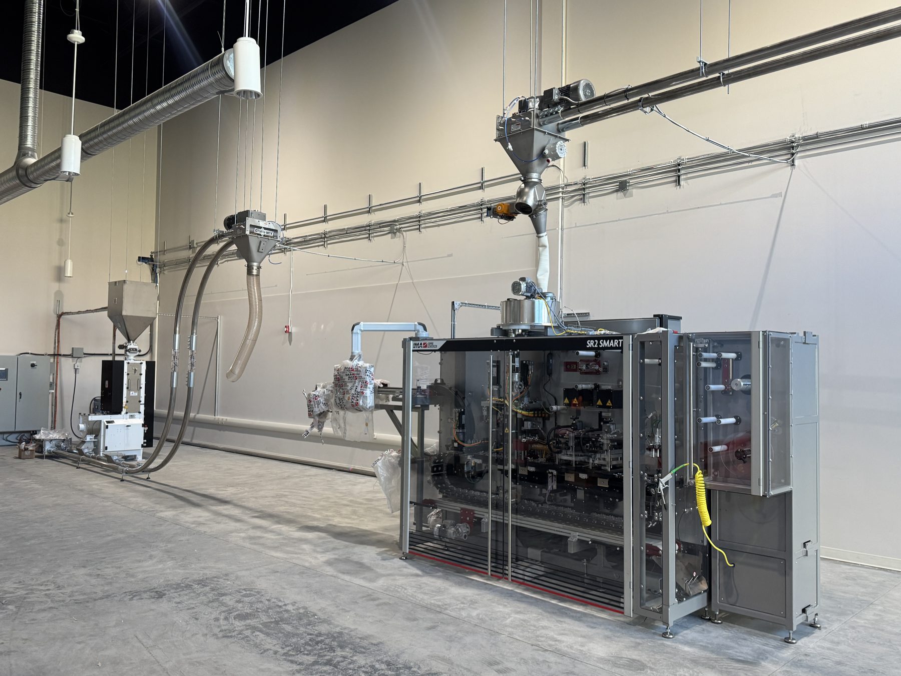 Industrial packaging machinery with conveyor and hoppers in an empty room — Eight Ounce Coffee