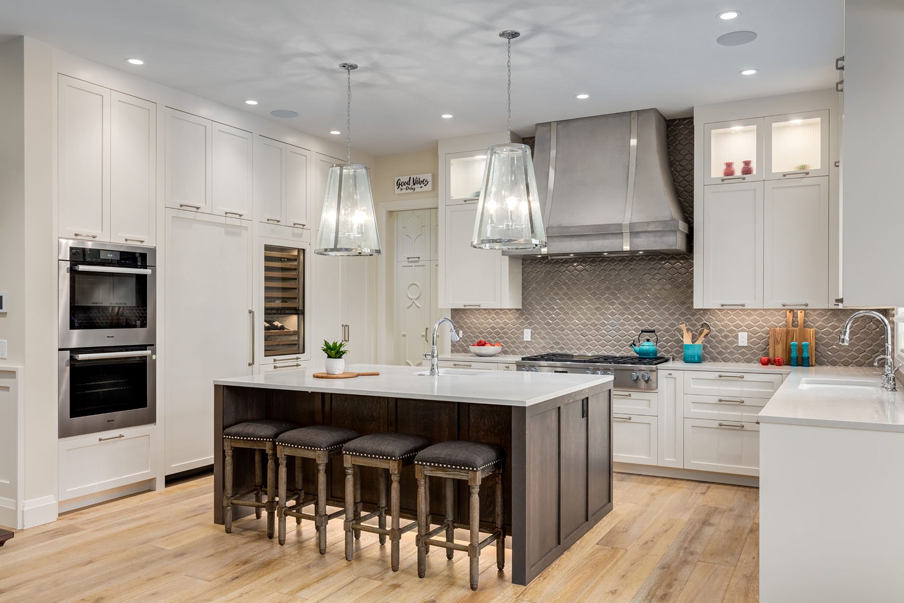 Modern kitchen with island, white cabinets, stainless steel appliances, and tiled backsplash — Artista