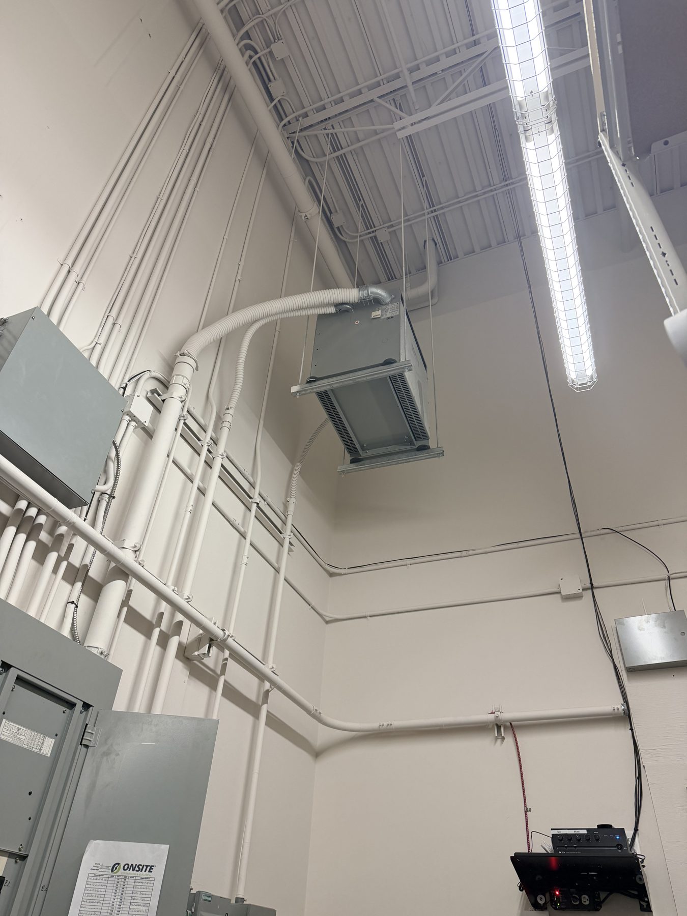Hanging HVAC unit, conduit, and electrical boxes in unfinished room — Skechers (Signal Hill)